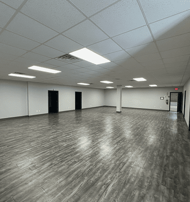 Empty room with wooden flooring and ceiling lights.