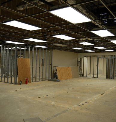 Interior of a building under construction with metal framing and ceiling lights.