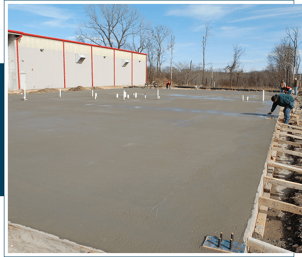 Workers smoothing freshly poured concrete on a construction site.