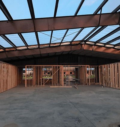 Framed open ceiling with wooden wall studs in construction site.